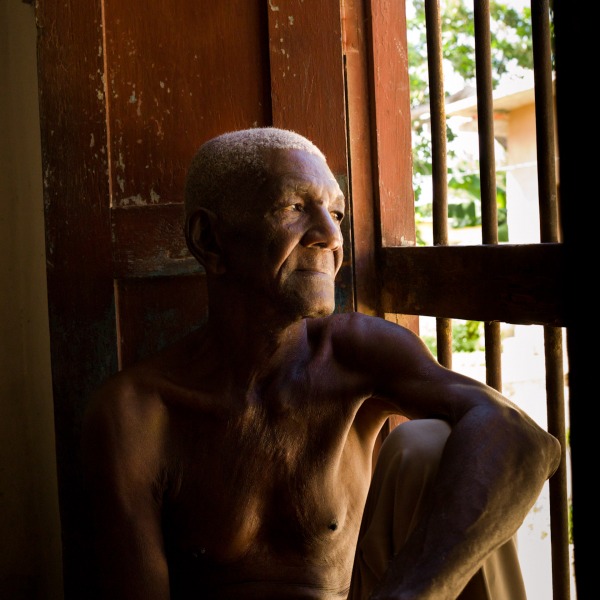 A retired cuban worker peers out the window of his home in Trinadad, Cuba.